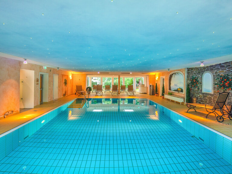Ein stilvolles Hallenbad im Braunschweiger Hof, umgeben von komfortablen Liegen.
