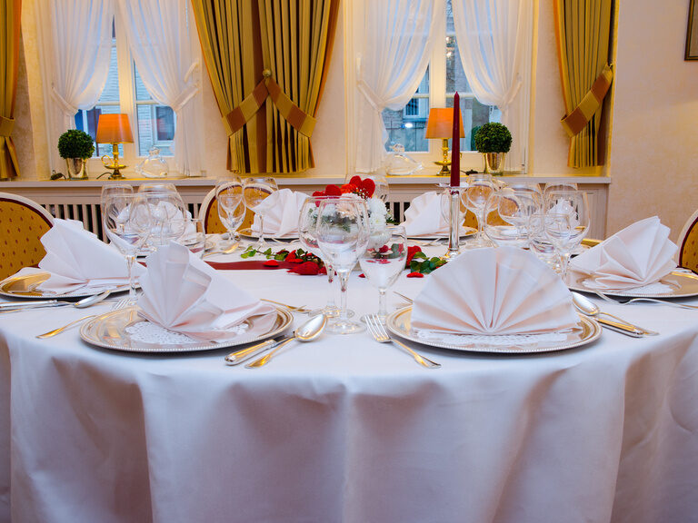 Elegant angerichteter Esstisch mit Tellern und Gläsern mit gemütlichen Stühlen im luxuriösen Restaurant des Braunschweiger Hofs.